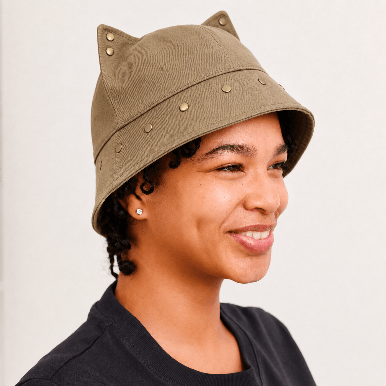 Model wearing a brown cat ear bucket hat with pointed 3D ears and subtle metal stud accents.