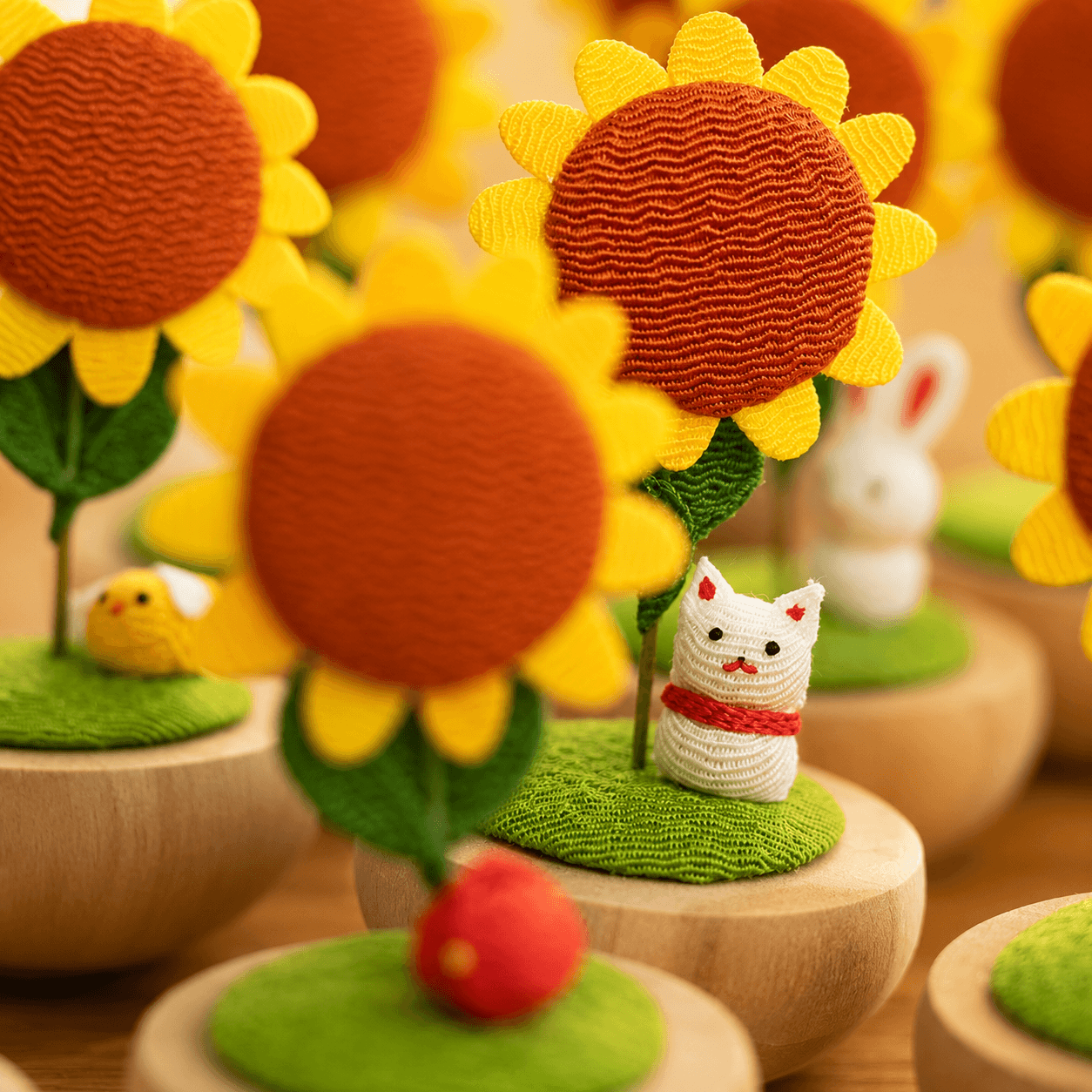 A collection of Japanese Handmade Sunflower Cat Ornaments by Ryukodo arranged on a wooden shelf.